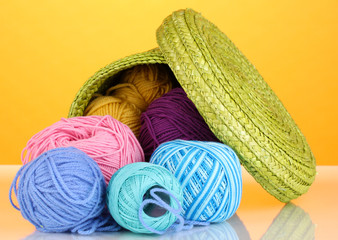 Colorful yarn for knitting in green basket on orange background