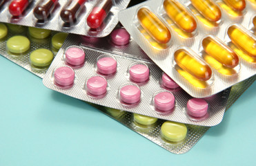Capsules and pills packed in blisters, on blue background