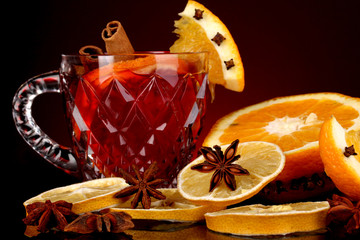 Fragrant mulled wine in glass with spices and oranges around