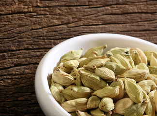 Bowl with cardamom over a wooden background