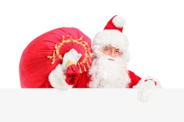 Santa Claus carrying a bag and posing behind a billboard