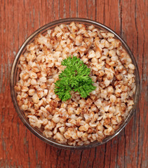 Buckwheat porridge with parsley in glass bowl, close-up