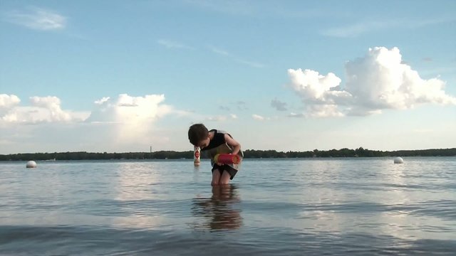 Boy in Lake Playing with Squirt Toy