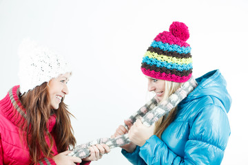 Two beautiful girls playing tug of war isolated on white backgro
