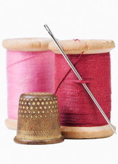 Old thimble and needle with pink and red thread