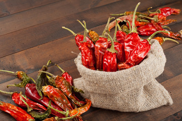 red chili peppers  in a canvas sack on wooden table
