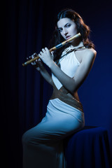 Obraz na płótnie Canvas Sensuality brunette plays a wooden flute