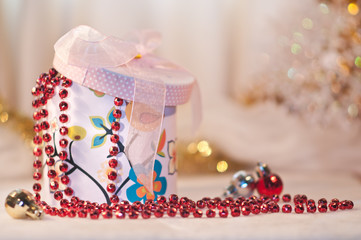 Gift box whith a red bead and christmas balls.