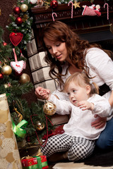 Happy mother decorating christmas tree with her baby