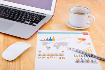 Financial chart on the table with laptop, coffee and pen