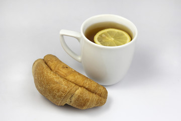 tea with lemon and croissant isolated on white
