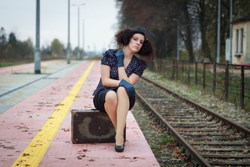 Girl waiting for train on empty railroad platform