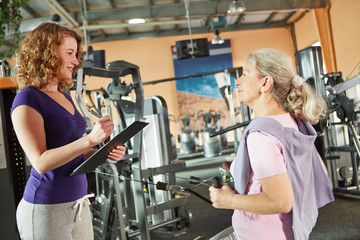 Seniorin am Kabelzug im Fitnesscenter