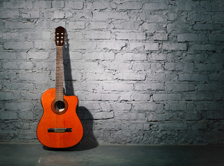 Fototapeta na wymiar Gitara akustyczna przechylony na ścianie grungy