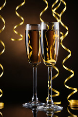 glasses of champagne and streamer on brown background