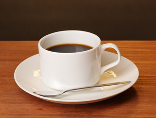 Coffee cup on wooden table on brown background