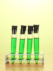 Test-tubes with green liquid on wooden table on green