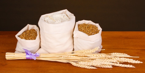 Flour and wheat grain on wooden table on dark background