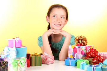 Little girl with gifts on yellow background