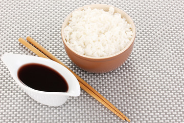 Bowl of rice and chopsticks on grey mat