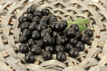 chokeberry with green leaf on wicker mat close-up