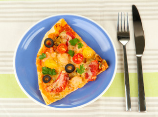 plate with a slice of delicious pizza on tablecloth close-up