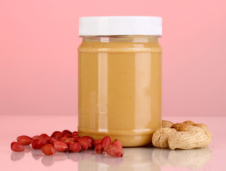 Delicious peanut butter in jar of peanut near on pink