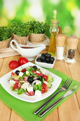 Fresh greek salad on plate on wooden table on natural