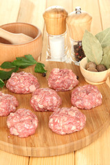 Raw meatballs with spices on wooden table