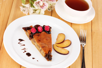 Tasty pie on plate on wooden table