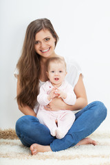 young mother and baby sitting on carpet