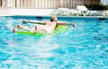 Junger mann auf einer grünen luftmatratze in einem schwimmbad