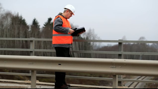 Engineer with a cell phone and a folder on the bridge