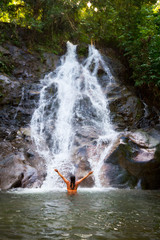 Woman refreshing herself in beautiful waterfall of Thailand