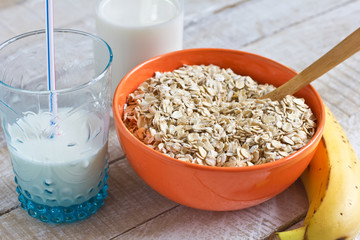 Oat flakes in bowl with banana and milk