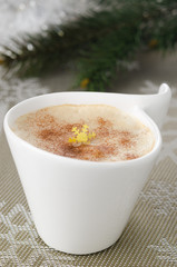 Cup of cappuccino on the table, fir branches in the background