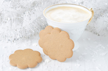 ginger biscuits, cup of cappuccino, Christmas tinsel on a white