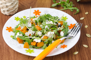 Salad with pumpkin, feta and arugula on a plate