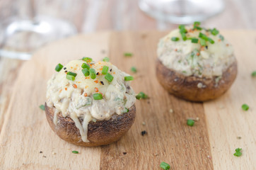 Stuffed mushrooms, baked with cheese and herbs on a wooden board