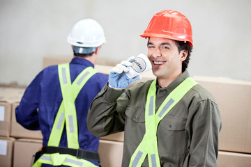 Foreman Drinking Coffee While Colleague Working At Warehouse