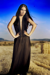 Naklejka premium Sexy young woman in black dress stadning in a stack of hay