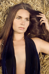 glamorous girl in a black dress lies on the hay
