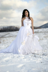 Fototapeta na wymiar pretty young woman posing in wedding dress on winter snow
