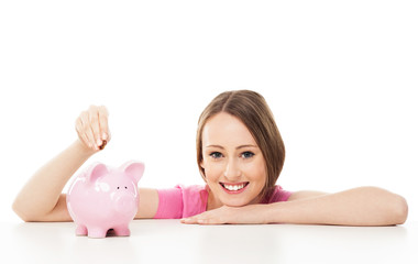 Young woman putting money in piggy bank