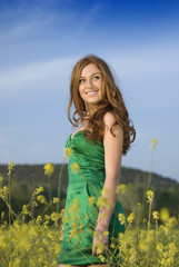 Naklejka na ściany i meble beautiful red-haired girl in a green field