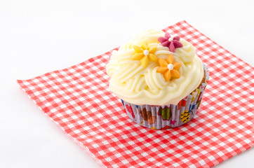 one cupcake buttercream on a red patterned napkin and flower