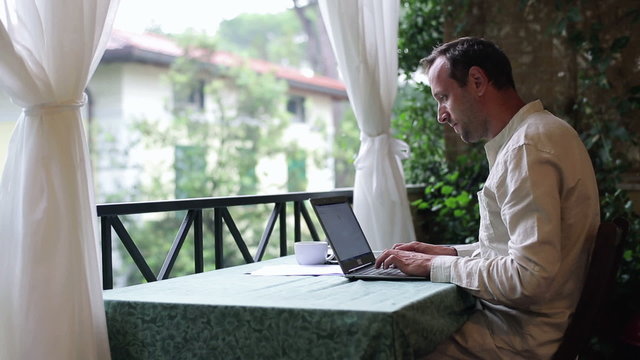 Portrait of smiling man with laptop computer relaxing on his bal