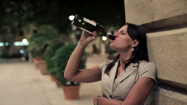 Young drunk woman drinking wine in the city, steadicam shot