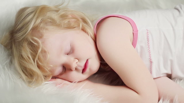 little blond girl sleeping on white bed