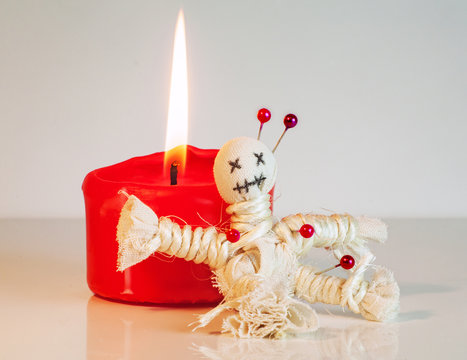eine Voodoopuppe sitzt an einer brennenden Kerze